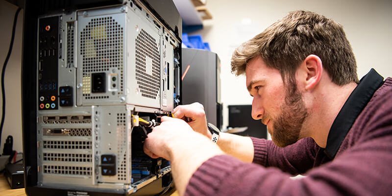 Student working on wiring inside a computer.